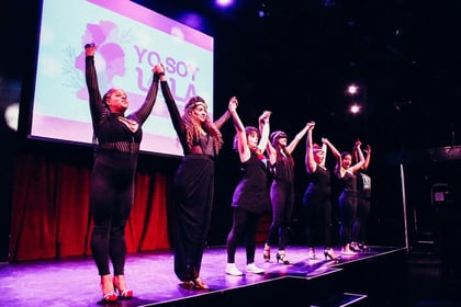 A row of performers standing on a stage in a line holding each others hands in the air ready to take a bow