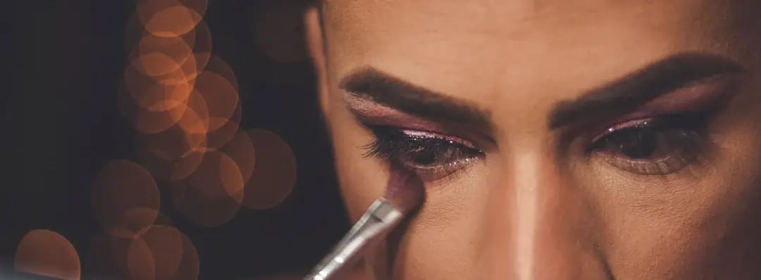 A close up of a drag artist's eyes and they are applying eye make up using a brush